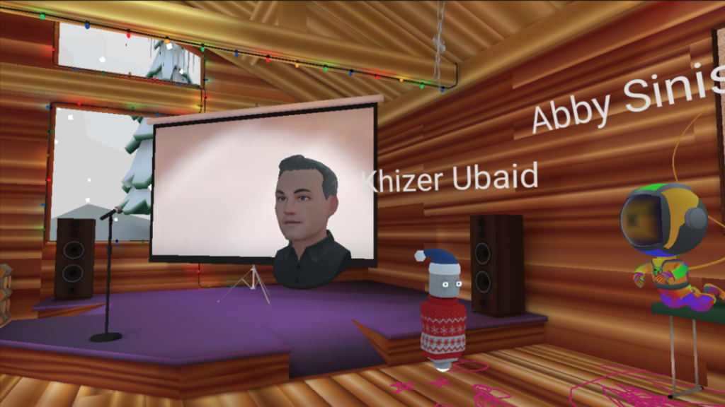 A floating head avatar of Professor C.C. Chapman inside a virtual log cabin with other various avatars floating around him. 